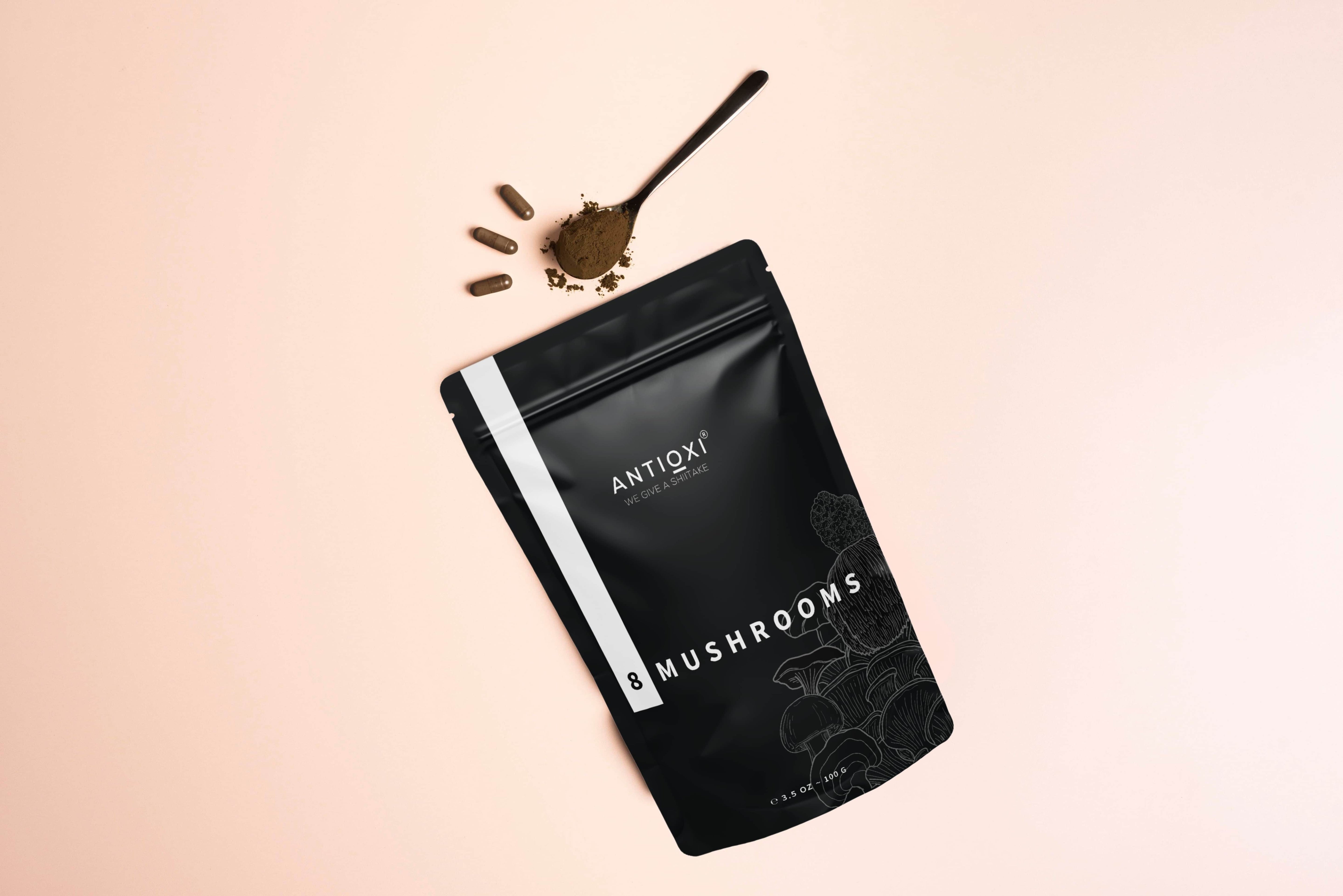 Antioxi 8 Mushrooms pouch with capsules and powder on a soft peach background.
