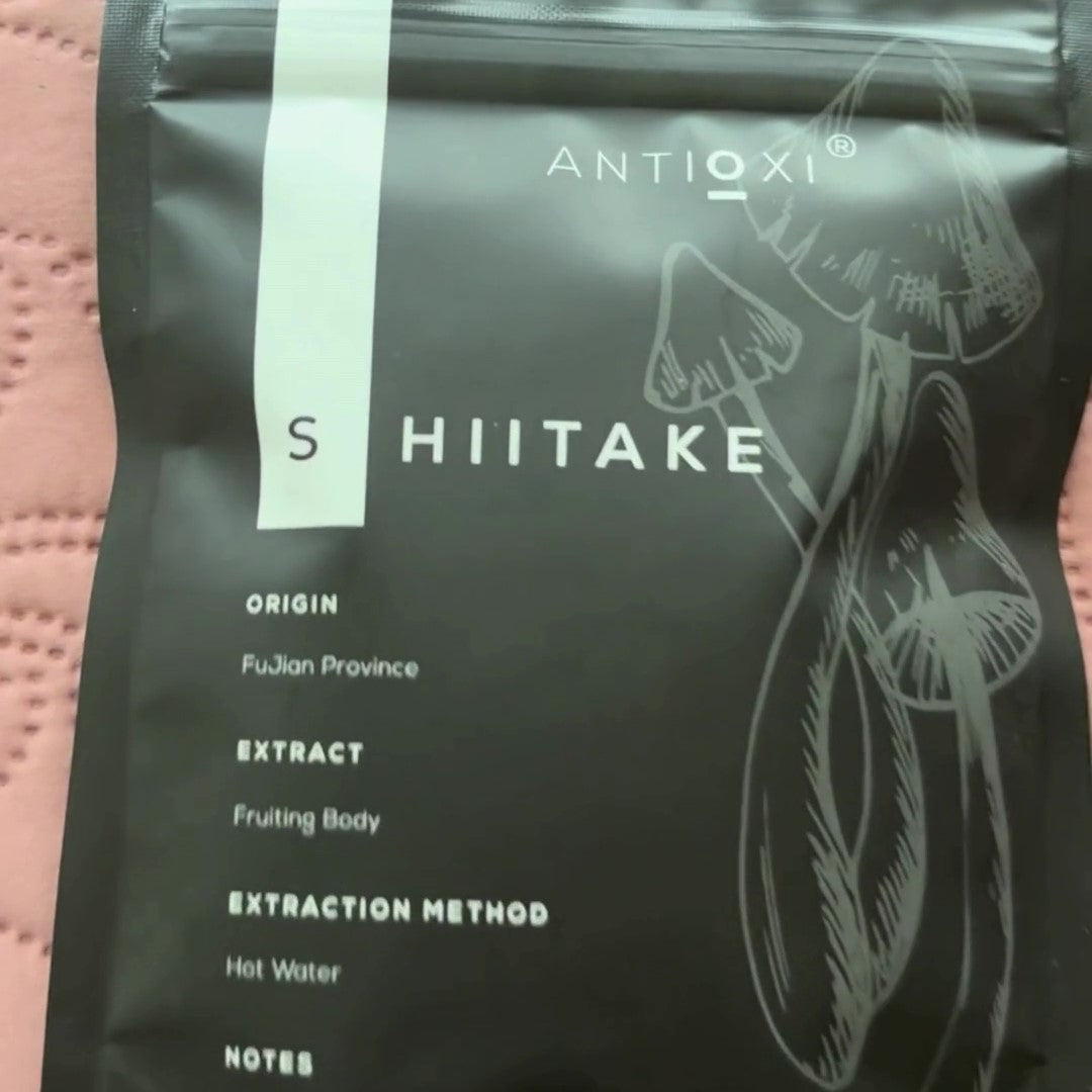 A pouch of Antioxi Shiitake mushroom supplements placed on a pink quilted surface.